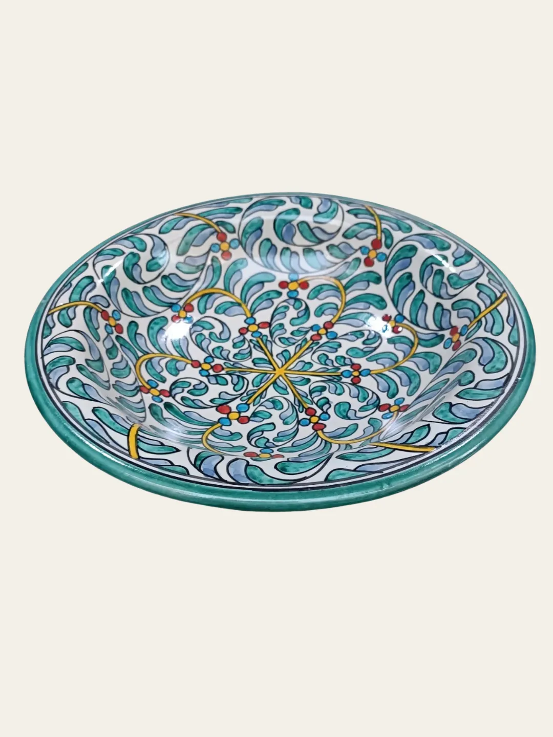 Close-up of the ceramic plate’s hand-painted teal, blue, yellow, and red motifs with dark outlines