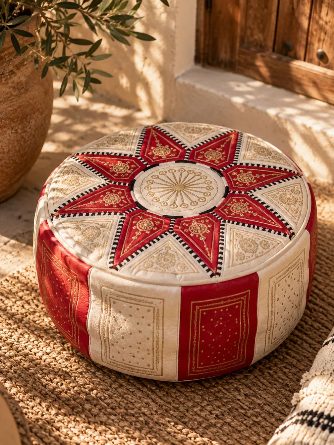 Close-up of red Moroccan leather pouf showing geometric panels and decorative stitching